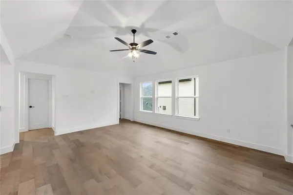 a view of empty room with wooden floor and fan