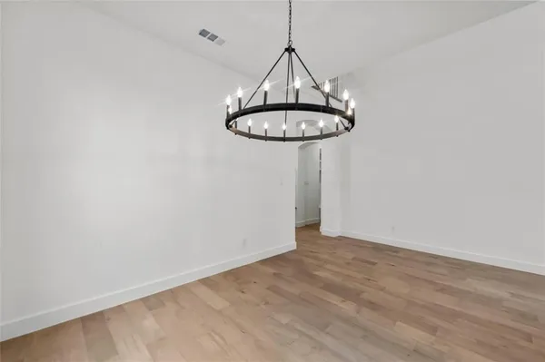 a view of a room with a hanging light and kitchen view