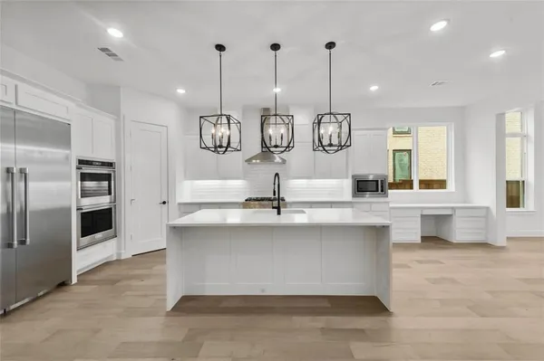 a very nice looking kitchen with granite countertop a large kitchen island white cabinets and stainless steel appliances
