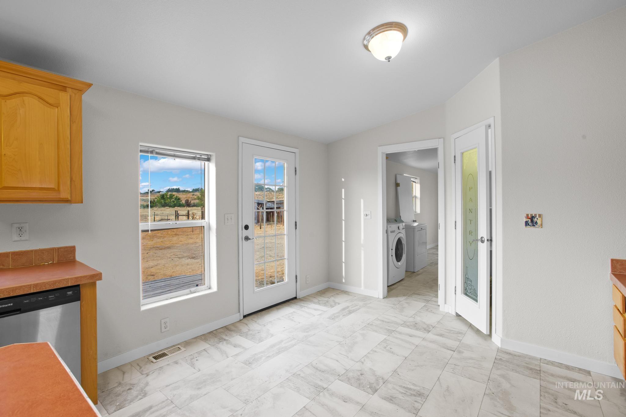 15190 Oasis Road Caldwell, ID 83607 - Photo 15 of 36 Light-toned cabinetry with a built-in dishwasher, white tile flooring, and a glass-paneled exterior door