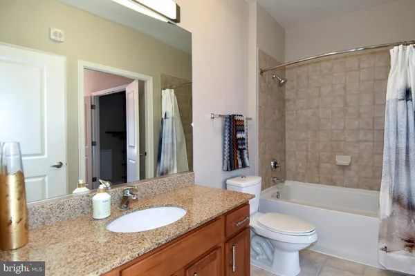 a bathroom with a granite countertop sink mirror vanity and toilet