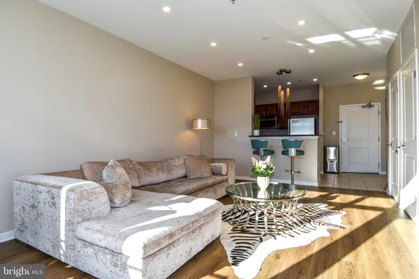 a room with stainless steel appliances kitchen island granite countertop a refrigerator a stove a microwave oven with white cabinets and wooden floor