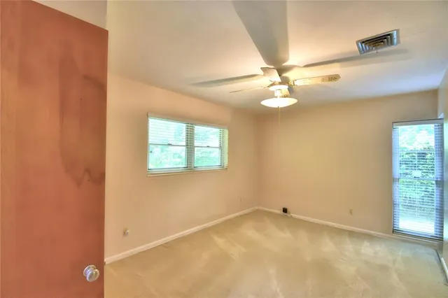 an empty room with a window and a ceiling fan