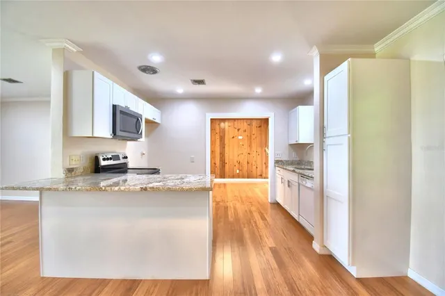 a large kitchen with a lot of counter space and wooden floor