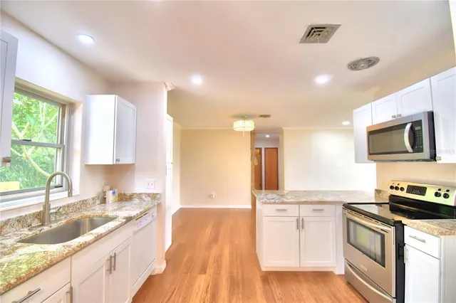 a kitchen with stainless steel appliances granite countertop a sink stove and microwave
