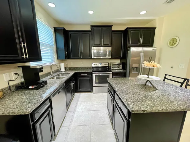 a kitchen with kitchen island granite countertop stainless steel appliances a sink stove refrigerator a sink and dishwasher