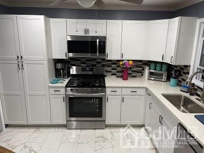 566 New Dover Road Colonia, NJ 07067 - Photo 2 of 23 a kitchen with stainless steel appliances a stove a microwave and a sink