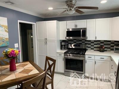 566 New Dover Road Colonia, NJ 07067 - Photo 5 of 23 a kitchen with a stove a microwave and cabinets