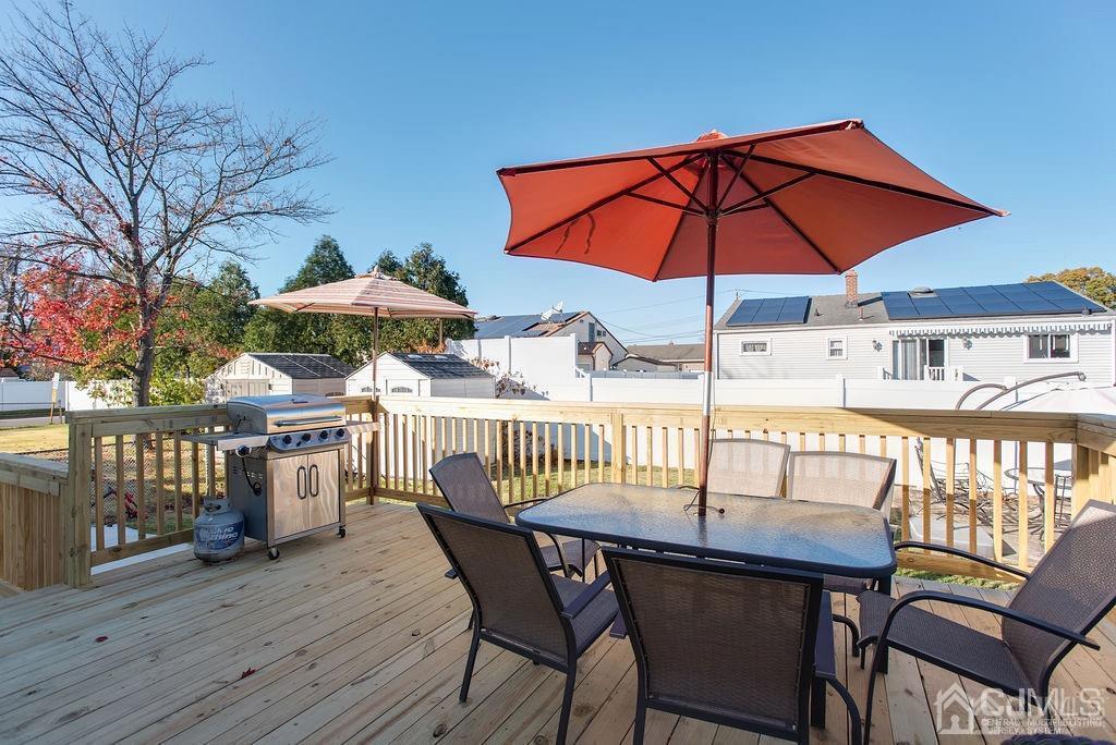 566 New Dover Road Colonia, NJ 07067 - Photo 7 of 23 a patio with a table and chairs under an umbrella with wooden floor