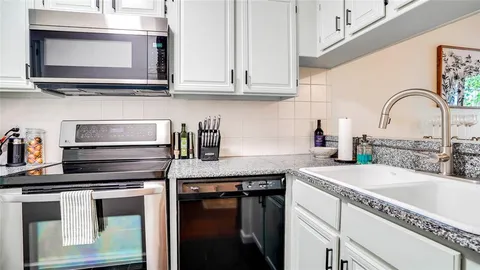 a view of kitchen with granite countertop white cabinets and a counter top space