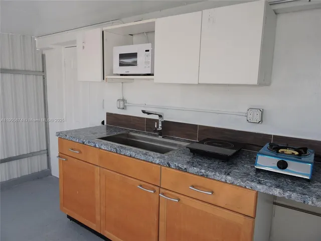 a kitchen with granite countertop a sink a stove and cabinets
