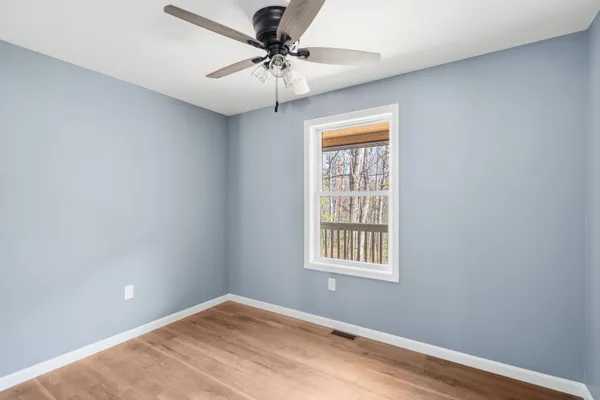 an empty room with a window and a fan