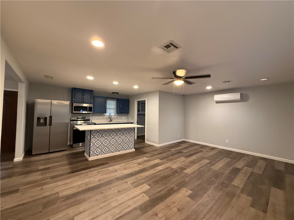 917 Corazan Street Alice, TX 78332 - Photo 11 of 37 an empty room with wooden floor and kitchen view