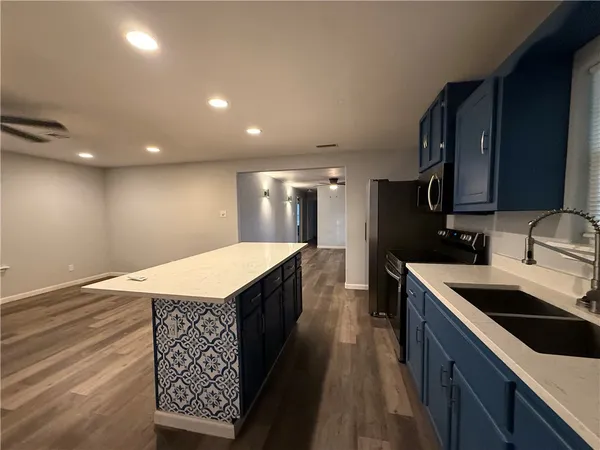 a kitchen with granite countertop a sink a counter top space stainless steel appliances and cabinets