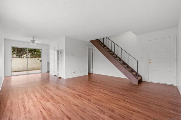 a view of an empty room with wooden floor and stairs