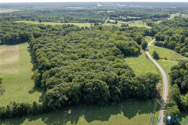 an aerial view of a residential houses with outdoor space and trees all around
