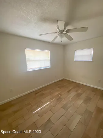 an empty room with a ceiling fan and window