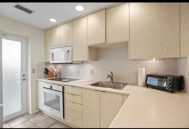 a kitchen with white cabinets and sink