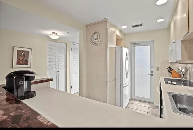 a view of a kitchen with fridge and workspace