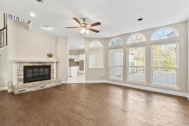 a view of an empty room with wooden floor and a fireplace