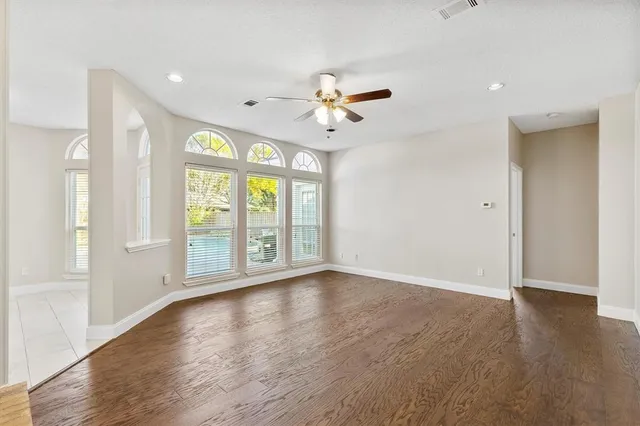 a view of an empty room with a window and wooden floor