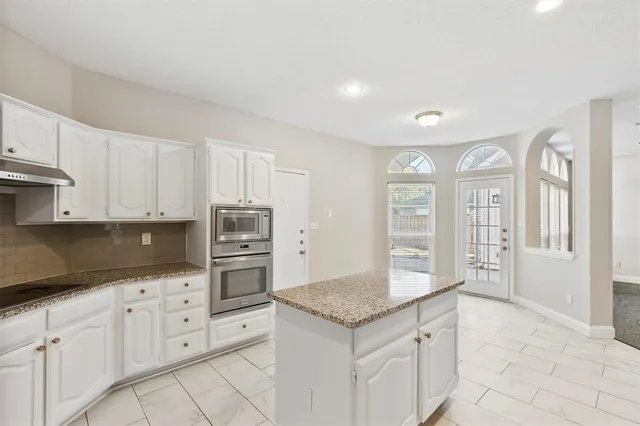 a kitchen that has a lot of white cabinets and stainless steel appliances