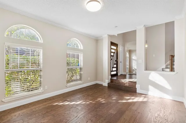 a view of an empty room with a window and wooden floor