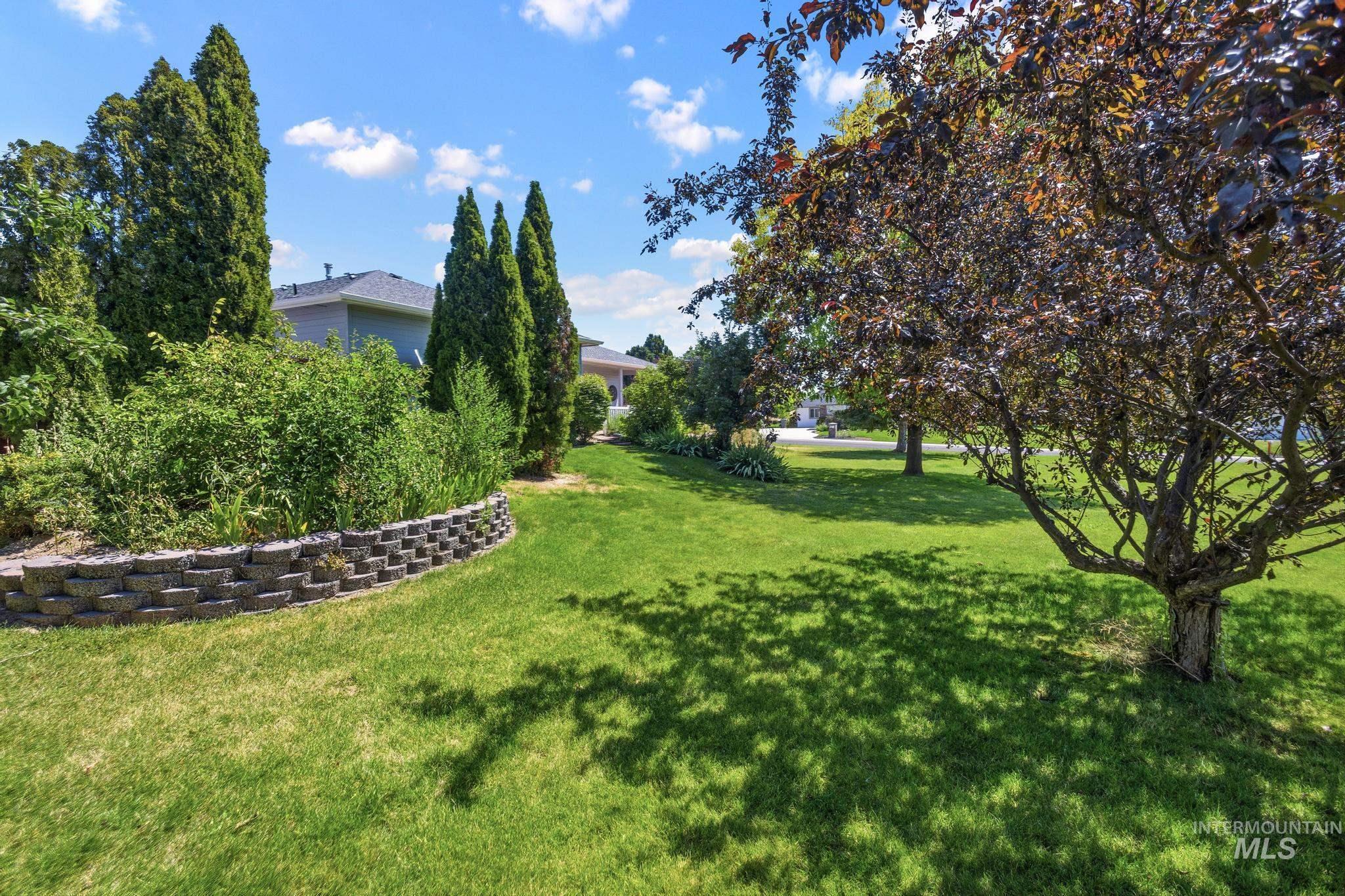 15181 Drury Way Caldwell, ID 83607 - Photo 38 of 49 Expansive lawn area featuring a mature ornamental tree, sculpted shrubbery, and a stone retaining wall