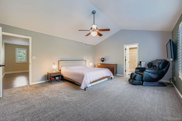 a spacious bedroom with a bed a couch and a chandelier