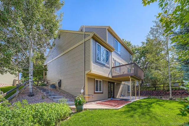 a view of a house with a yard and a large tree