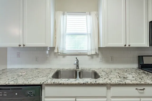 a kitchen with granite countertop a sink window and cabinets