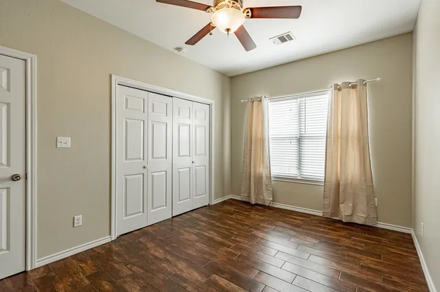 a view of empty room with wooden floor and fan