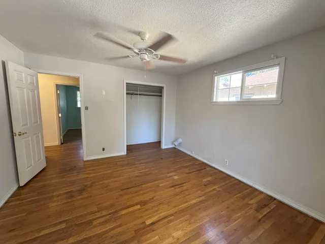 a view of an empty room with wooden floor and a window