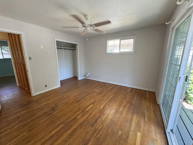 an empty room with wooden floor and windows
