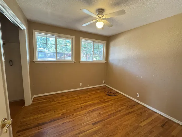 an empty room with wooden floor and windows