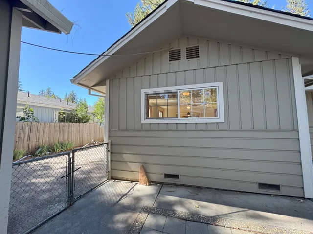 a view of a house with a small yard and wooden fence