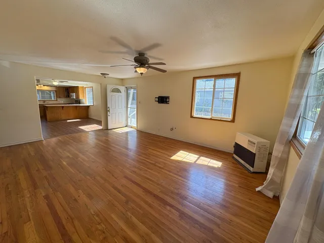 a view of an empty room with wooden floor and a window