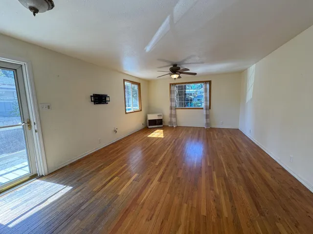 an empty room with wooden floor and windows