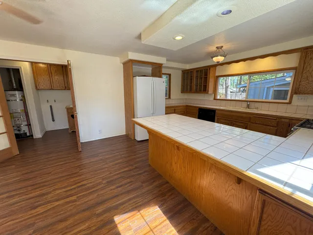 a large living room with stainless steel appliances kitchen island granite countertop wooden floor a large window and a sink