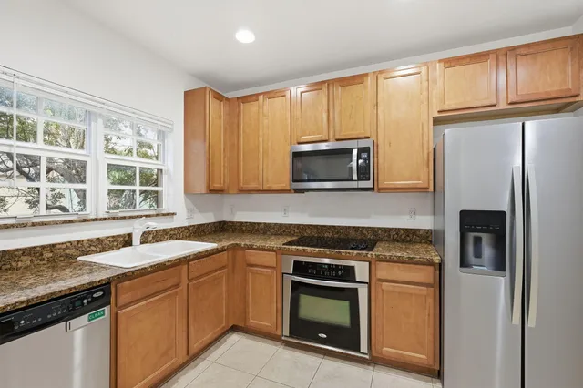 a kitchen with granite countertop a sink stove and refrigerator