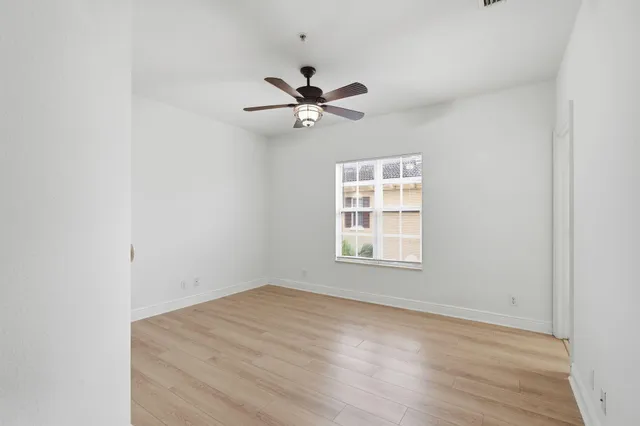 an empty room with a window and a ceiling fan
