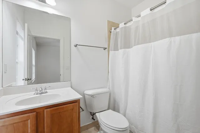 a bathroom with a sink a toilet a mirror and shower curtain