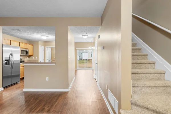 a view of a hallway with wooden floor and a kitchen