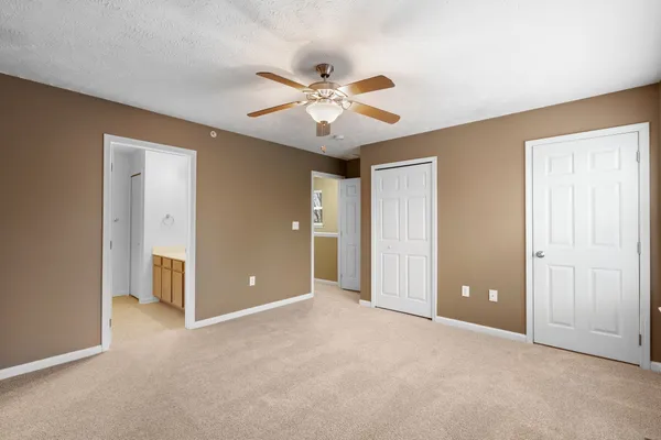 an empty room with closet and a ceiling fan