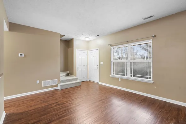 a view of an empty room with wooden floor and a window
