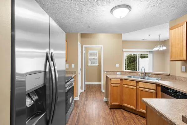a kitchen with stainless steel appliances granite countertop a refrigerator a sink and white cabinets