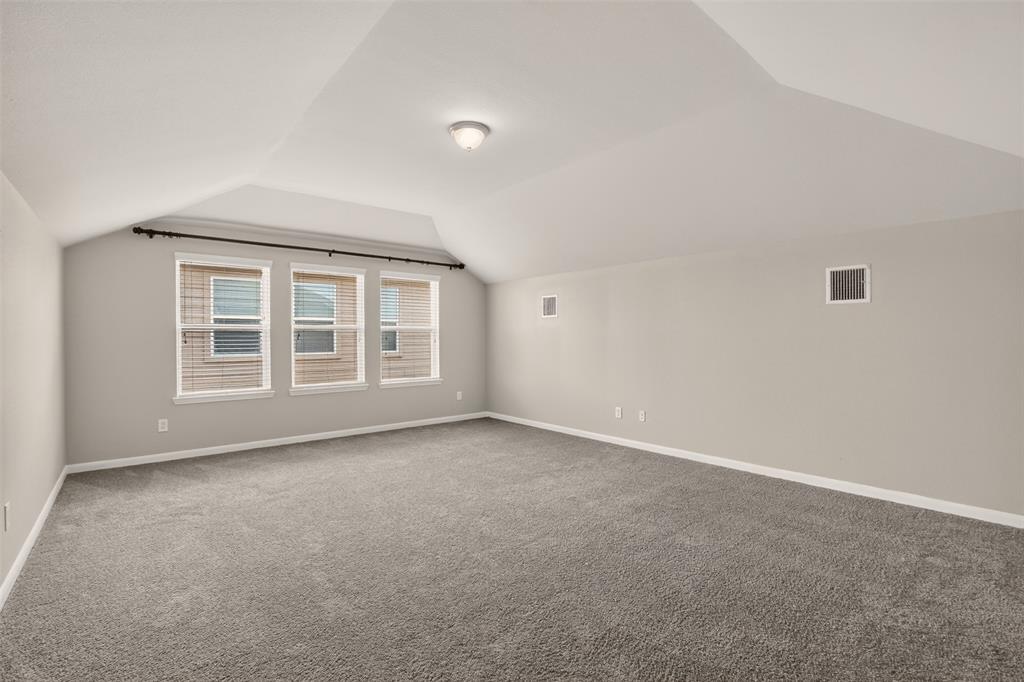 9105 Switchgrass Lane Forney, TX 75126 - Photo 14 of 20 Spacious room featuring vaulted ceilings, three large windows with blinds, neutral carpeting, and light-toned wall paint