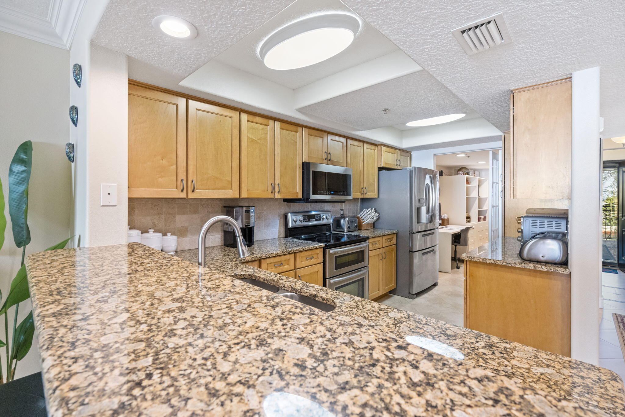 2375 South Atlantic Avenue, Unit 302 Cocoa Beach, FL 32931 - Photo 7 of 36 a kitchen with granite countertop a stove a sink and a microwave