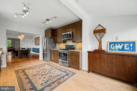 a open kitchen with stainless steel appliances granite countertop a refrigerator oven stove a sink dishwasher and a dining table with the view of living room