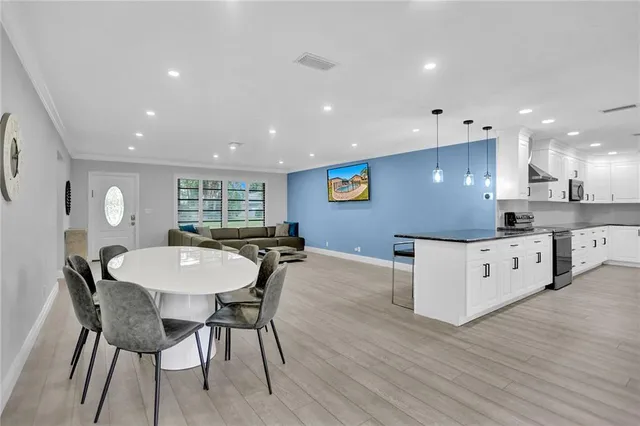 a kitchen with stainless steel appliances kitchen island granite countertop a table chairs sink and cabinets